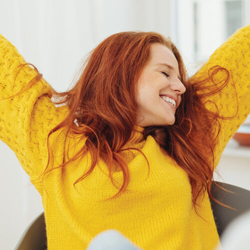 Smiling woman in yellow sweater representing vibrant branding for Quality Dental Group